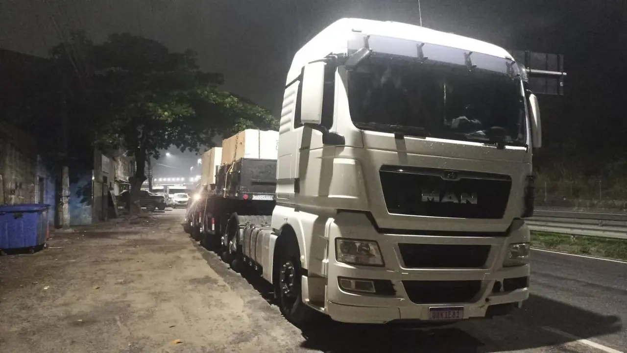 Carreta MAN carregada com chapas, saindo à noite